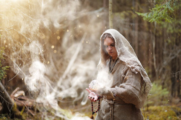 Fototapeta na wymiar A man in a cassock spends a ritual in a dark forest
