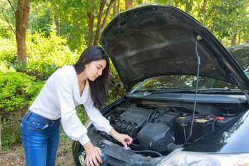 Asian woman with a broken car with open hood.