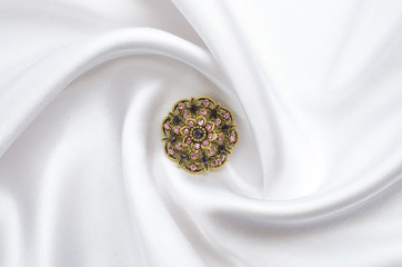 round brooch with gems on silk