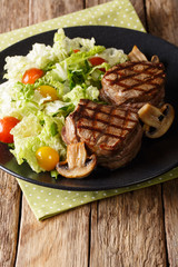 Grilled filet mignon steak with vegetable salad and mushrooms close-up. vertical