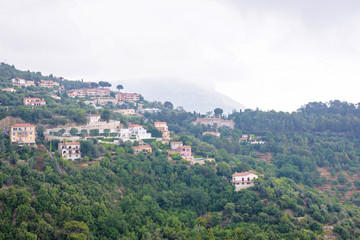 Fototapeta na wymiar Daylight foggy view to Eze village, trees and mountains from castle