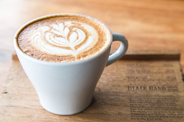 Cappuccino in white glass with wire drawing on milk froth.