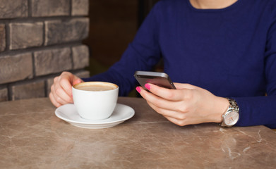 Woman hand texting on phone in cafe