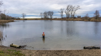 Mann mit Weihnachtsmütze geht in einen See zum Baden
