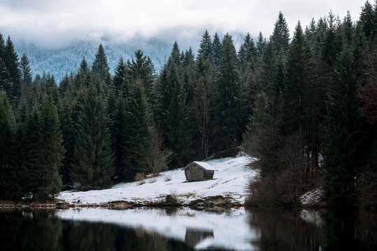 Lake Geroldsee overlooking a forest with cabin with the Karwendel Mountains in Background in Bavaria, Germany in winter