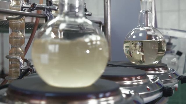 Bulb with boiling liquid close-up. Flask is heated with large temperature on the stove in laboratory. Change the focus between the foreground and background. Scientific experiment.