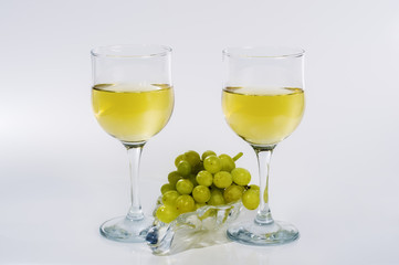 Two glasses of white wine and a bunch of green grapes on a glass plate / Picture made in the personal Studio of a photographer