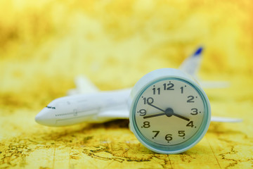 Travel and Time Concept. Close up of vintage round clock with miniature airplane toy model on world map.