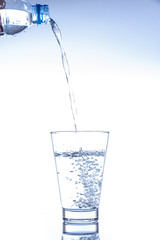 Pouring water and splashing in the glass with reflection on mirror.