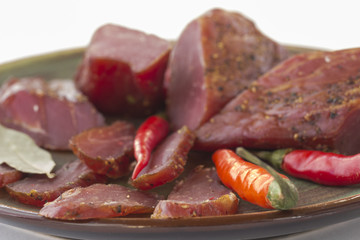 Slices of smoked meat and chili on a green ceramic plate.