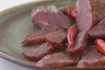 Slices of smoked meat and chili on a green ceramic plate