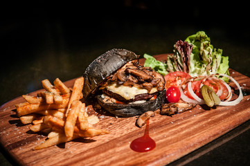 Beef charcoal black burger with french fries cheese and vegetable