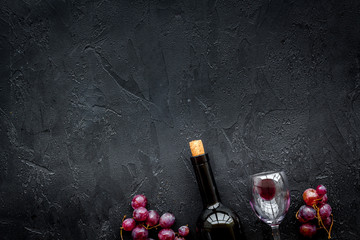 Drink wine concept. Bottle, glass, grape on black background top view copyspace