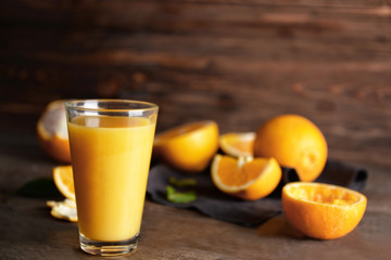 Glass of fresh orange juice on wooden background