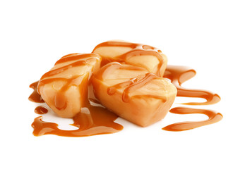 Delicious candies with caramel sauce on white background
