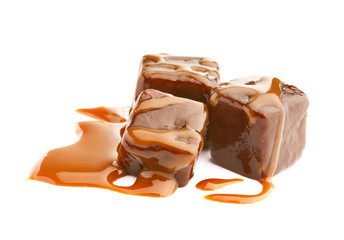 Delicious candies with caramel sauce on white background