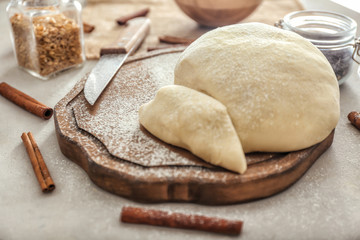 Wooden board with raw flaky dough on table