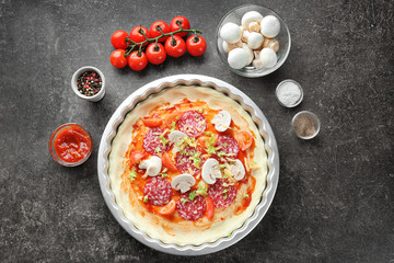 Raw dough with ingredients for pizza on table