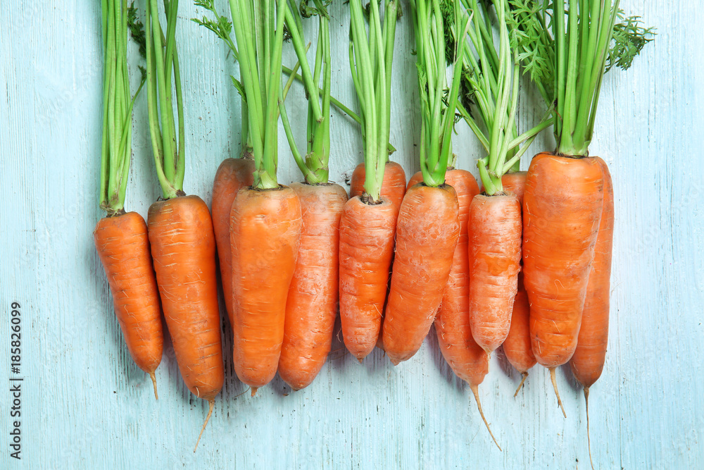 Poster many ripe carrots on light wooden background