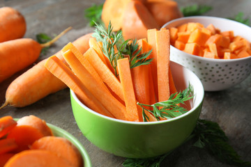 Bowl with carrot sticks on table, closeup