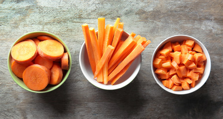 Bowls with cut carrot on table, top view