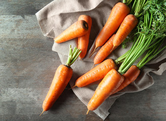 Tasty ripe carrots on wooden background, top view