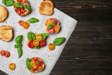 Tasty bruschettas with tomatoes on parchment, top view