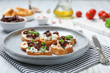 Tasty bruschettas with sun-dried tomatoes on plate, closeup