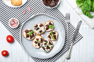 Tasty bruschettas with sun-dried tomatoes on plate, top view