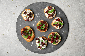 Tasty bruschettas with sun-dried tomatoes on slate plate