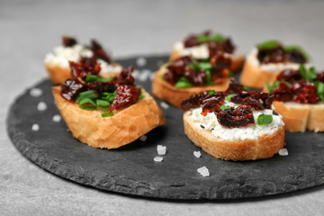 Tasty bruschettas with sun-dried tomatoes on slate plate