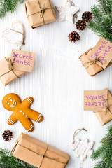 Christmas game Secret Santa. Gift boxes near spruce branch and gingerbread cookies on white wooden background top view copyspace