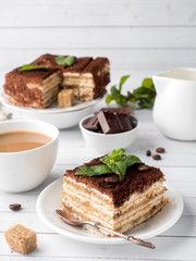 Tiramisu Dessert with Mint and Cup of Coffee on White Wooden Table