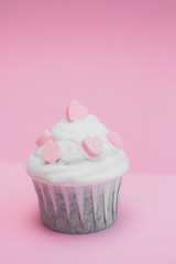 cute cupcake decorated with pink hearts on a pink background