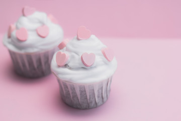 cute cupcakes decorated with pink hearts on a pink background