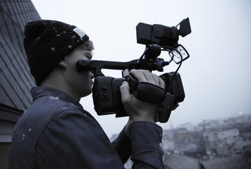 Cameraman in the winter on the street, the snow falls from the sky