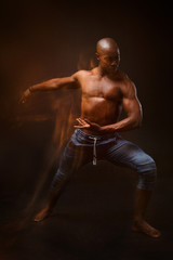 Fototapeta na wymiar Dancing black man on a black background with a mixed light.
