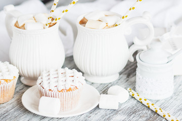 Cups with cacao and marshmallow, cupcakes and different decorations, wooden background