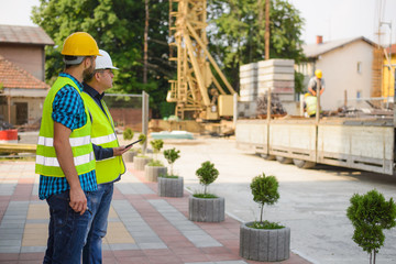 Workers in hardhat and green jacket posing on building site