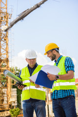 Workers in hardhat and green jacket posing on building site