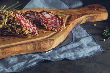 Close-up of salami in spices on tye rustic wooden cutting board on a table