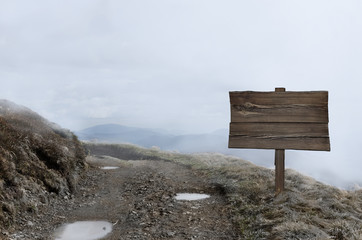 Wooden sign near the road in bright mist