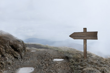 Wooden direction sign in bright mist