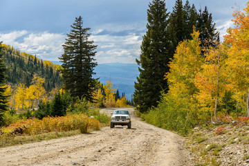 Autumn Mountain Road - Autumn view of a 4X4 SUV climbing up a steep and rugged mountain road,...