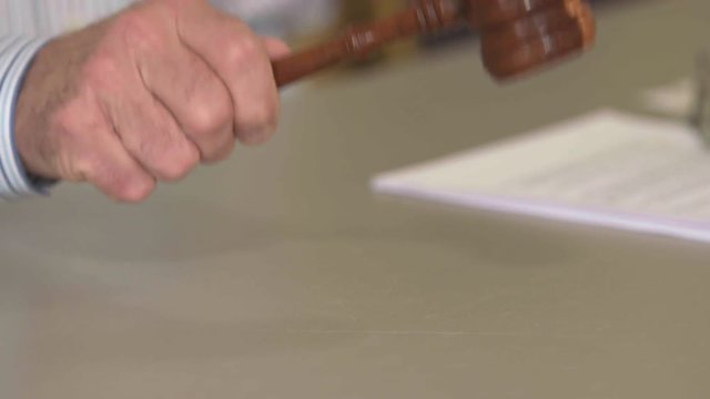 Slow motion (48fps) ProRes clip of a man's hand picking up a gavel, banging it, then setting it down. Shot in 4K UHD.