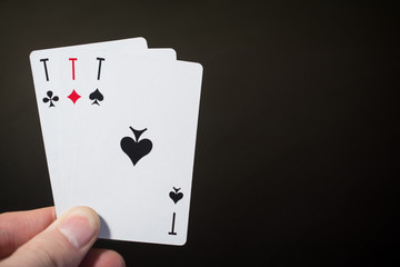 Abstract: man hand holding playing card three ace isolated on black background with copyspace poker set four eight