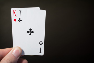 Man hand holding playing card ace of clubs and kind isolated on black background with copyspace abstract