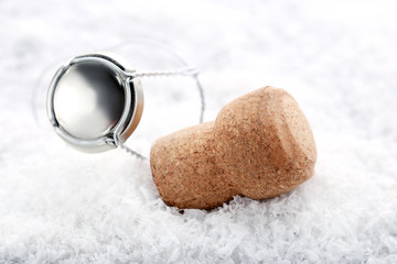 Champagne cork with cap on white snow