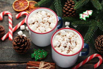 Cappuccino with marshmallow in mugs and fir-tree branches on wooden table