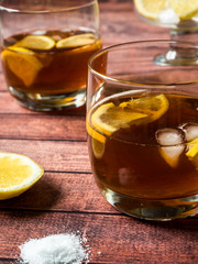 Glasses of cocktail with ice and lemon on wooden table close-up